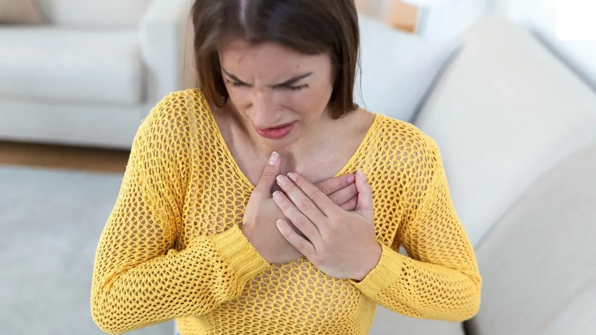 A woman holding her chest, with a concerned expression