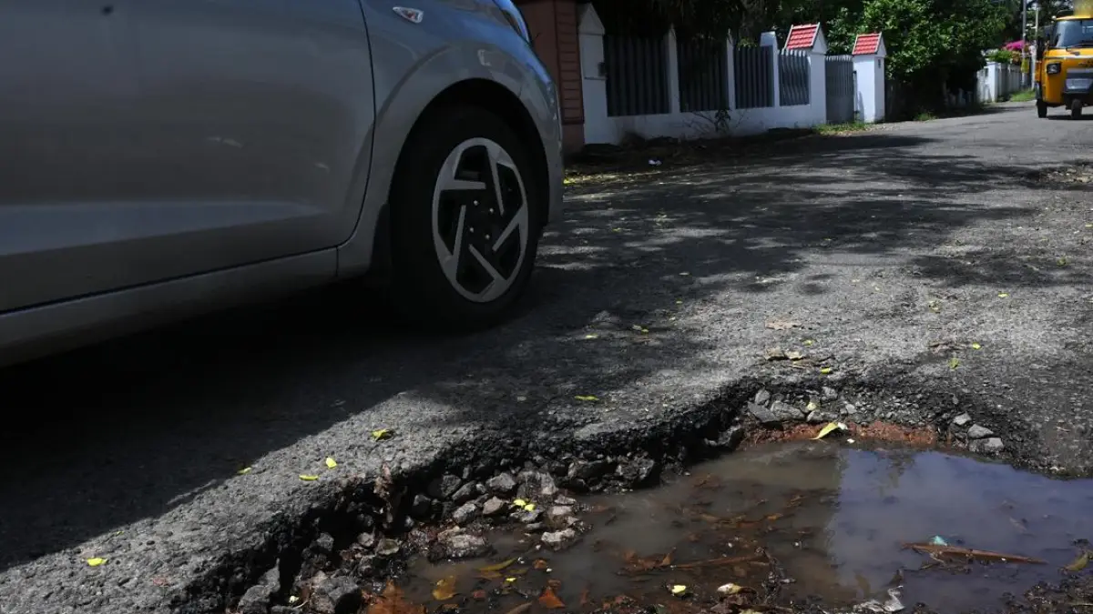 A photo of a damaged road in Kochi, with potholes and traffic congestion