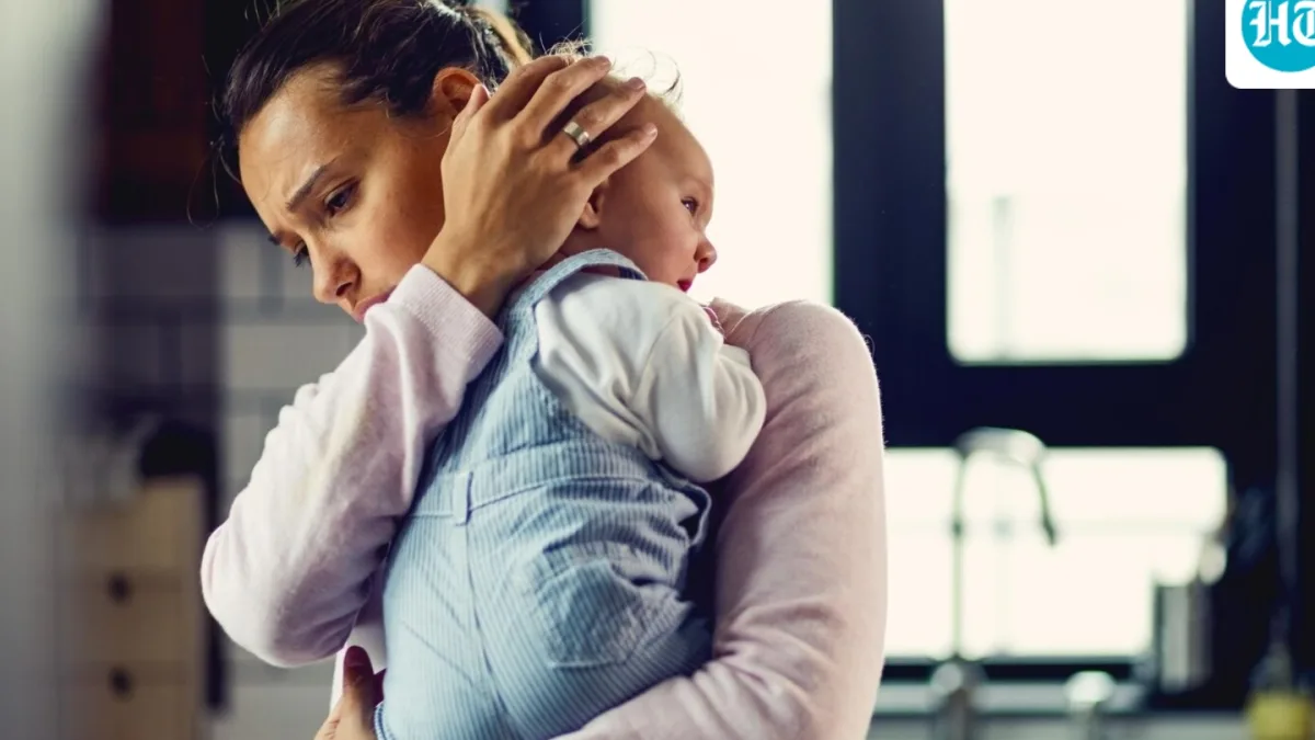 A new mother holding her baby, with a subtle expression of sadness