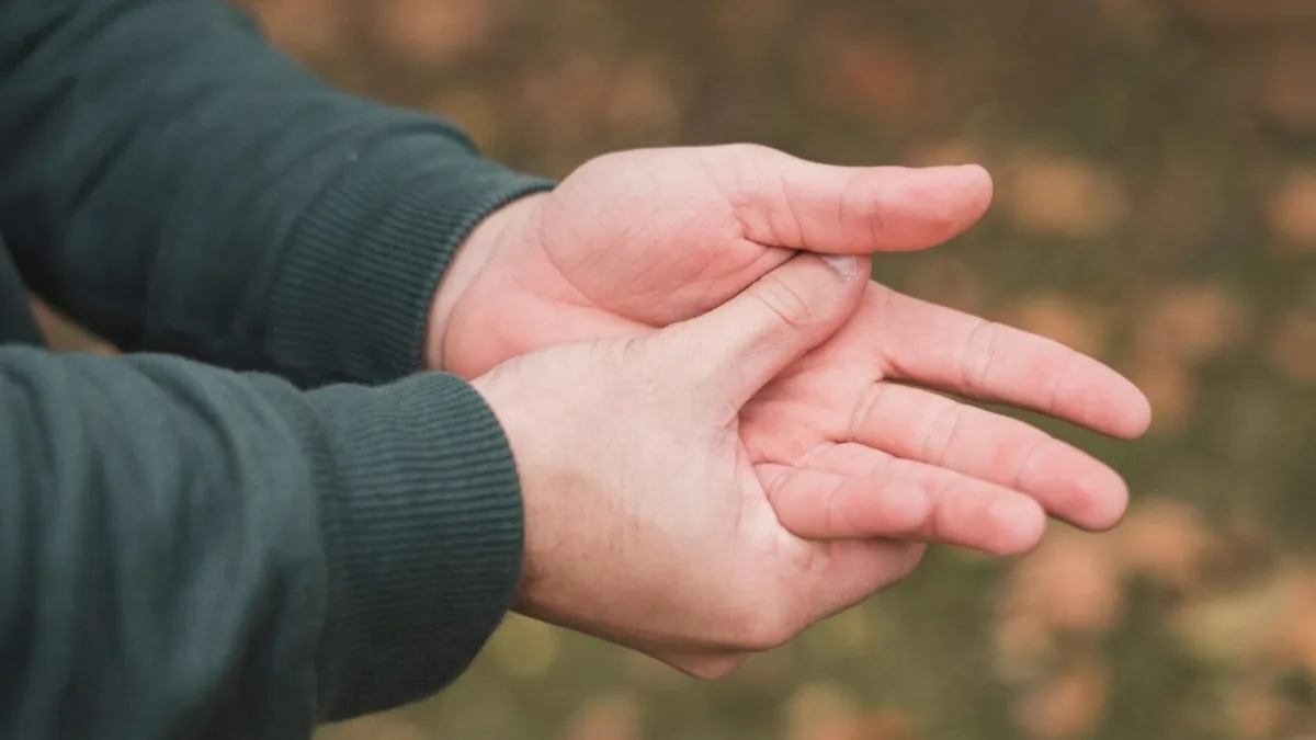A person holding their stiff fingers in the morning