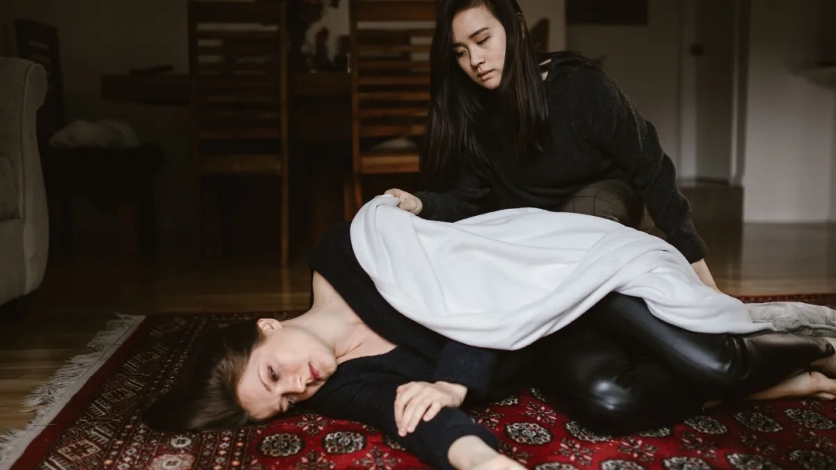 A person experiencing a seizure, with someone providing first aid