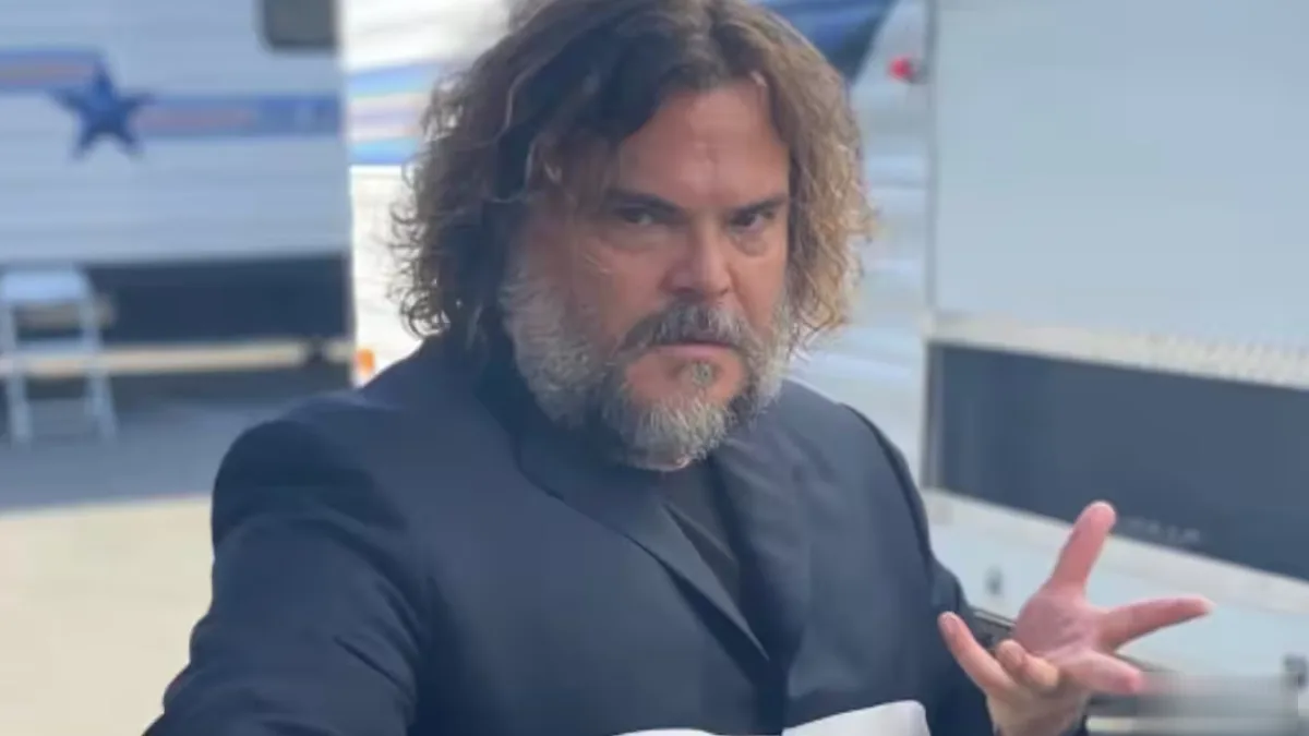 Jack Black smiling and holding a guitar