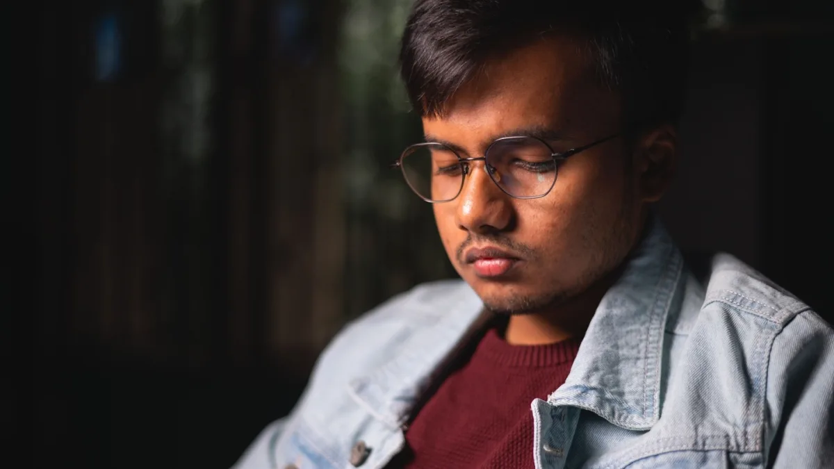 A person sitting on a couch, looking concerned