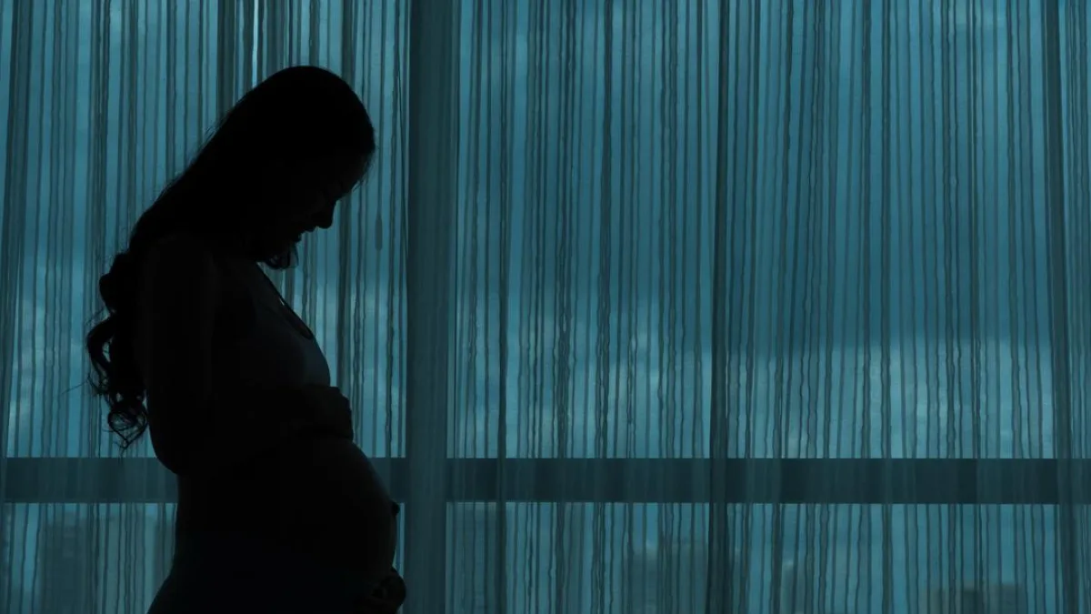 A pregnant woman sitting on a couch, looking concerned